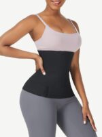 Woman wearing the black tummy wrap band, side view with hand on hip.