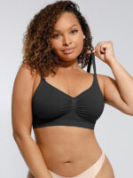 Woman wearing the black seamless shaping bra with adjustable straps, holding the strap.