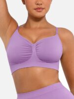 Woman wearing the dark purple seamless shaping bra with adjustable straps, holding the strap.