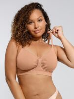 Woman wearing the dark skin seamless shaping bra with adjustable straps, holding the strap.