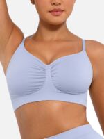 Woman wearing the light blue seamless shaping bra with adjustable straps, holding the strap.