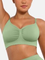Woman wearing the light green seamless shaping bra with adjustable straps, holding the strap.