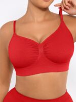 Woman wearing the red seamless shaping bra with adjustable straps, holding the strap.