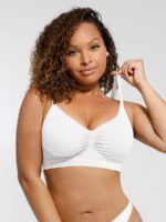 Woman wearing the white seamless shaping bra with adjustable straps, holding the strap.
